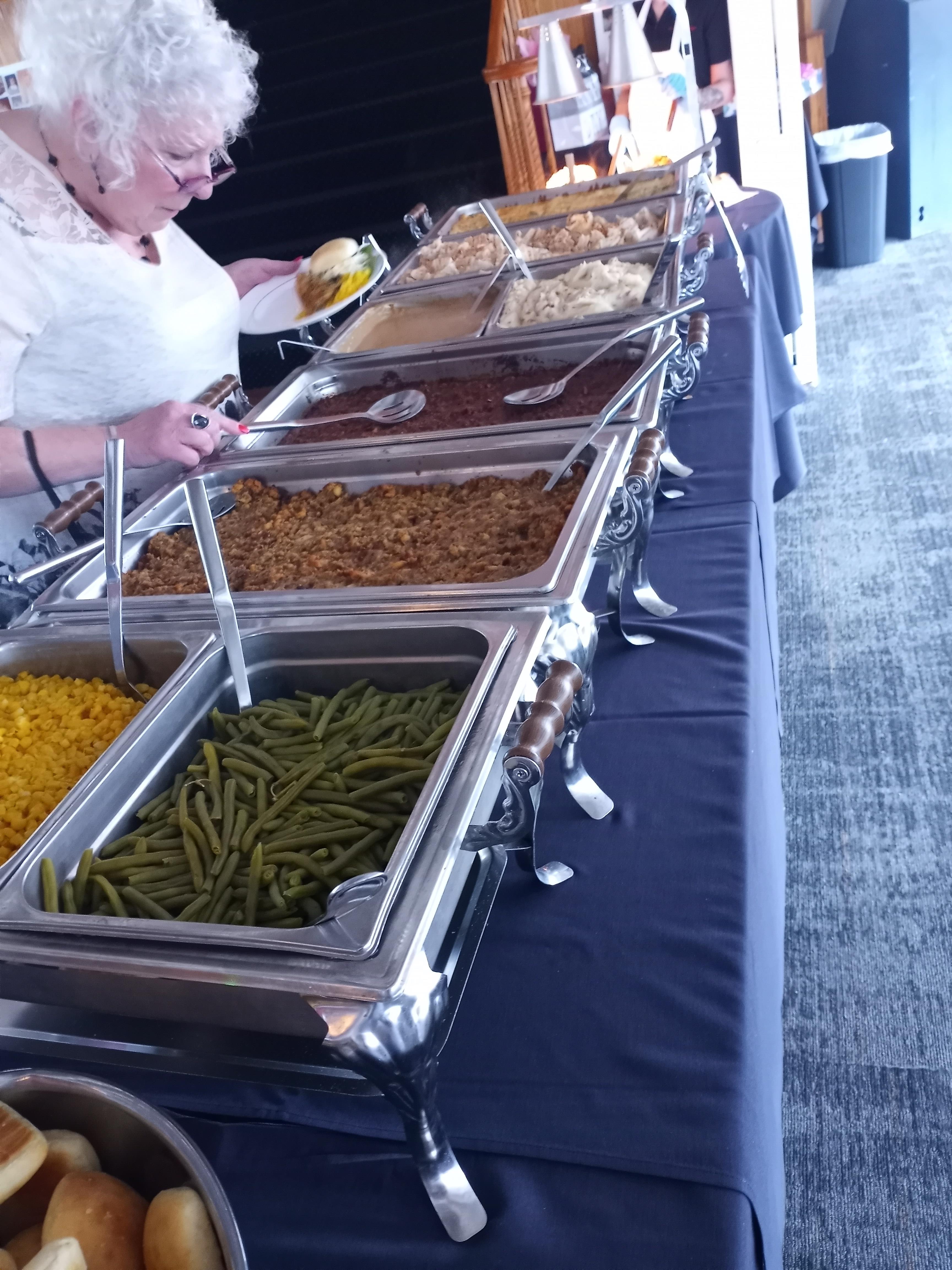 A woman stands before a buffet table at a senior activities event near me